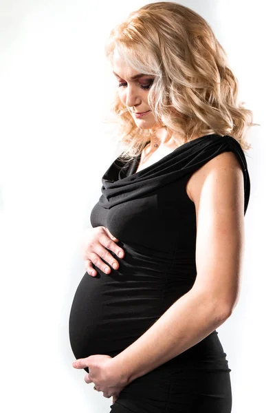 Genç ve güzel hamile bir kadın pembe arka planda duruyor. — Stok fotoğraf