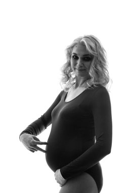 Genç ve güzel hamile bir kadın pembe arka planda duruyor.