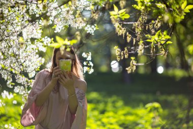 Kiraz çiçeklerinin bahçesindeki güzel genç bayan.
