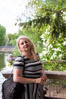 Çiçek bahçesindeki leylak kokusunun tadını çıkaran güzel genç bir kadın.