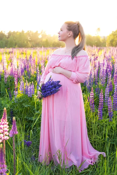 Retrato de la niña embarazada en un campo floreciente en el sol al atardecer — Foto de Stock