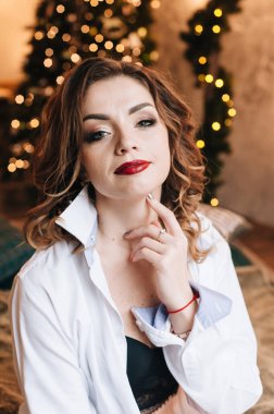 Noel için güzel bir genç kız. Mutlu bir ruh hali içinde. Arka planda bir Noel ağacı ve kapalı alanda ışıklar var.