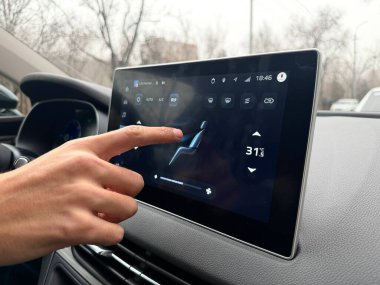 Modern bir araba infotainment dokunmatik ekranında dijital klima kontrol sistemini elle çalıştırmak. Sıcaklık, havalandırma ve havalandırma ayarları için yüksek teknoloji arayüzü.