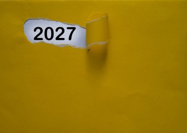 Yeni yıl iş planları ve yeni yıl çözümleri kavramında sarı kapaklı kağıt üzerinde 2027, kağıt üzerinde tipografik 2027 ile yeni yıl konsepti
