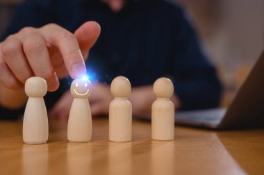 Doğru Aday Çalışanların Seçim Süreci Seçiliyor. İşadamı lideri ofisteki dizüstü bilgisayarda çalışırken bir grup çalışanın arasından tahta insanları tutuyor ve seçiyor.