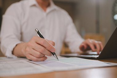 İşadamı, şirketin mali bütçe raporunu analiz etmek için tablet üzerinde kalem ve iş bilgileri ve bilgisayar bilgisayarı kullanıyor ve ofis odasının geleceği için çalışma ve planlama masraflarına mal oluyor