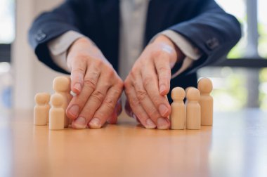 Avuç içi kullanan bir iş adamı, iş yerinde çatışma ve çözüm kavramında iki ahşap insanı birbirinden ayırır. Çatışma ve arabuluculuk yönetim kavramının çözümü.