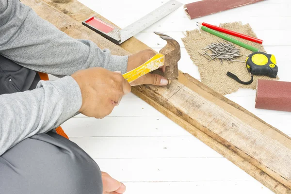 Erkek marangoz kullanarak çekiç ve iş yerinde tırnak. Arka plan usta aracı