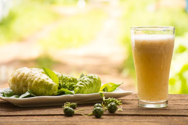 Noni ve noni suyu ahşap arka plan üzerinde. Suyu sağlık veya meyve sağlık için ya da sağlık için ot için. Açık görünüm