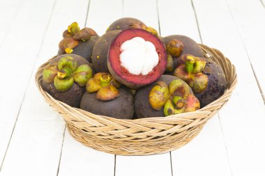 Ahşap beyaz arka planda sepet içinde mangoteen ve mangoteen dilim. Üstteki görünüm ve yakınlaştırma