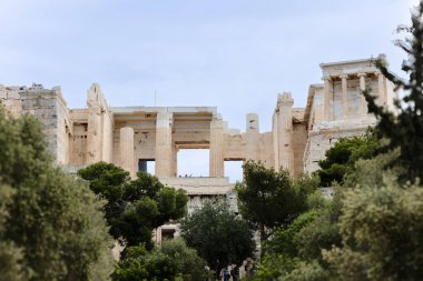 Kaba antik taş mimarisine dikey olarak yakın çekim, iki büyük kemerli açıklık, parlak gökyüzüne karşı çerçevelenmiş, negatif alanı vurguluyor