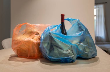 Çevre dostu bir kese kağıdından şarap ve yiyecek paketlerini açan elin dikey yakın çekimi. Sürdürülebilirlik ve tüketime odaklan