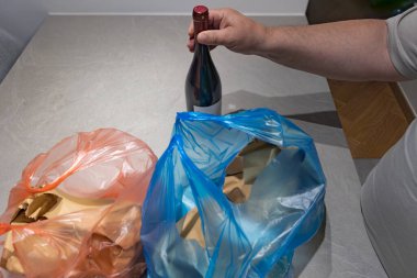 Çevre dostu bir kese kağıdından şarap ve yiyecek paketlerini açan elin dikey yakın çekimi. Sürdürülebilirlik ve tüketime odaklan