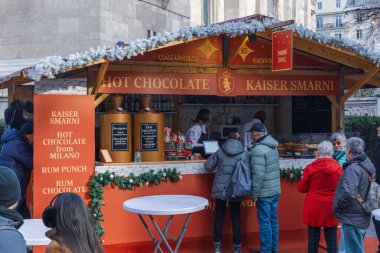 BUDAPEST, HUNGARY - 18 ARALIK 2025: Bir Noel pazarındaki şenlik desenli barbekü tezgahında müşterilerin yatay arka plan görüntüsü