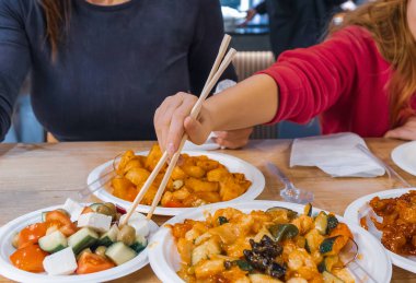 Geniş açılı bir bakış açısıyla, bir kadın ve bir çocuğun, fotokopi alanı olan modern bir WOK restoranında Çin yemekleri yerken çekilmiş.