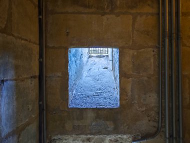 Taş bir duvarda parmaklıkları olan pencere
