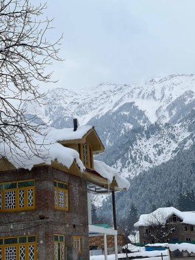 Kashmir 'de güzel bir ev Soğuk bir kış gününde Karla kaplı dağların altında