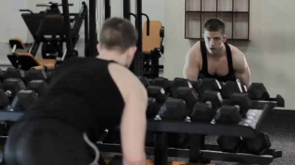 Muscular athlete trains with dumbbells — Stock Video