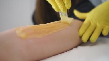 Güzellik uzmanı güzellik merkezinde kadın bacağı ağdalıyor. Ayakların titremesi için prosedür.