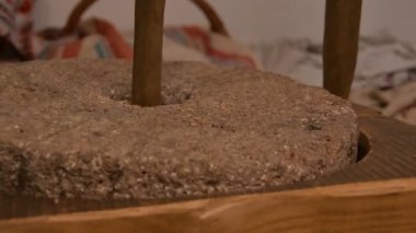 Eski bir ortaçağ el yapımı değirmen taşı değirmeni üzerinde öğütülmüş kuru mısır tohumu, eski Quern taş el değirmeni kuru mısır tohumu.