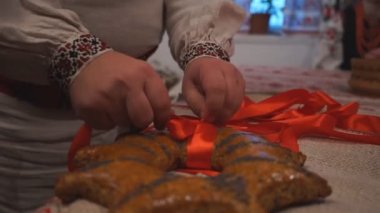Bir adam fırıncı masaya zencefilli ekmek koyar ve onu kırmızı kurdeleyle bağlayıp eski bir ayini gerçekleştirir.