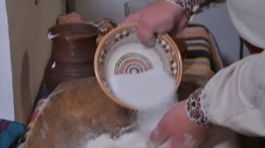 Kırsalda ekmek yapmanın eski bir yolu. Bir adam antika bir tabakta elleriyle hamuru karıştırıyor..