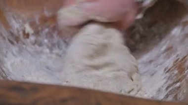 Kırsalda ekmek yapmanın eski bir yolu. Bir adam antika bir tabakta elleriyle hamuru karıştırıyor..