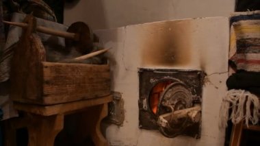 Yuvarlak kütükler taş bir fırında yanıyor. Sıcak kömürler ısı yayar.