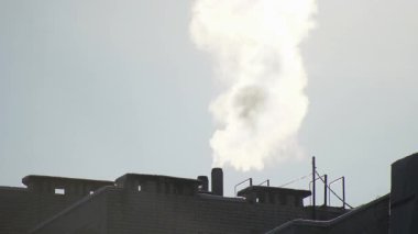 Bir apartmanın ısıtma borusundan beyaz duman çıkıyor.