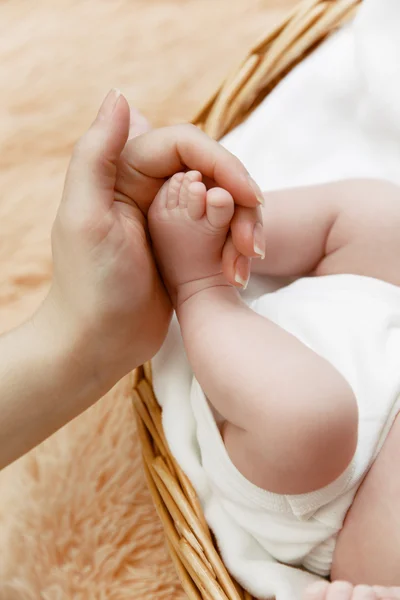 Mãe segura pequeno pé de seu bebê recém-nascido — Fotografia de Stock