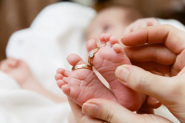 Babys pies con anillos de boda en las manos de las madres — Foto de Stock