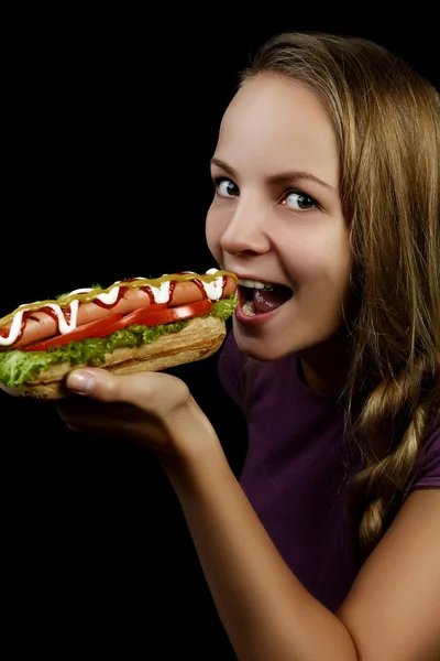 Jovencita comiendo un perrito caliente — Foto de Stock