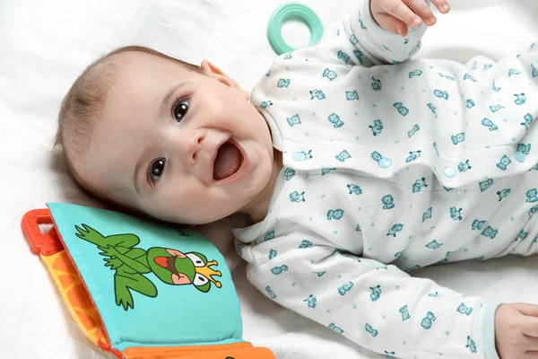 Criança feliz deitada em sua cama com brinquedos — Fotografia de Stock