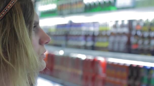 Beautiful woman thinks which beverages to buy — Stock Video