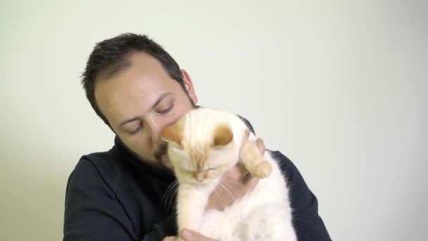 Giovane uomo si preoccupa di un gatto sul suo grembo - Punto rosso Siamese — Video Stock