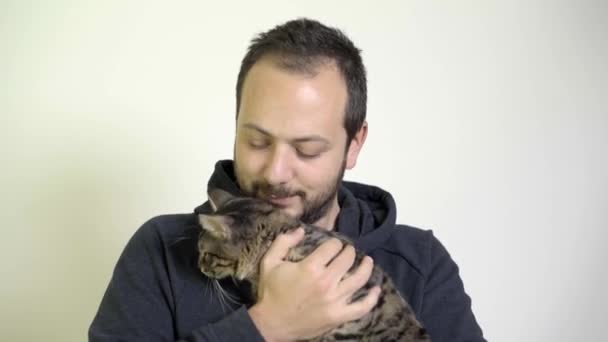 Ung Man bryr sig - gillar en kattunge på honom knä — Stockvideo