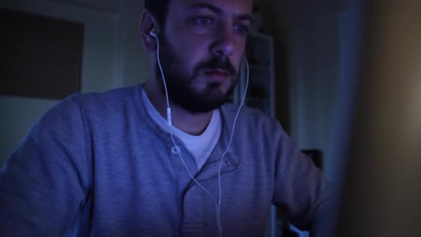 En man listes musik medan han använder datorn — Stockvideo