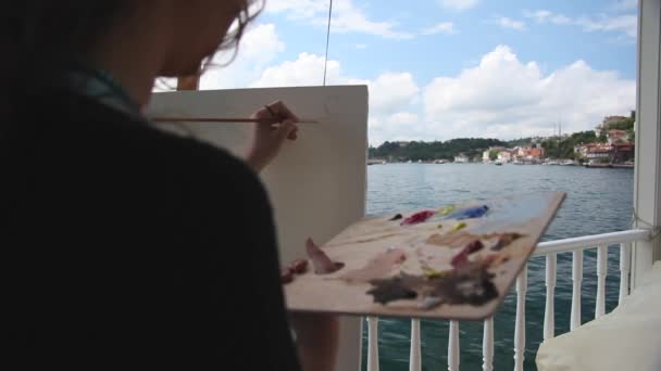 Mujer artista pintando con pincel junto al mar — Vídeo de stock