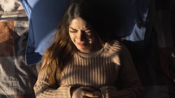 Молодая женщина плачет в постели — стоковое видео