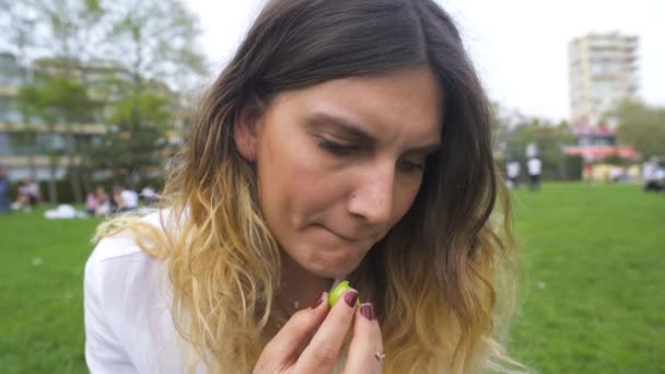 Jovem mulher se senta no parque e come frutas — Vídeo de Stock