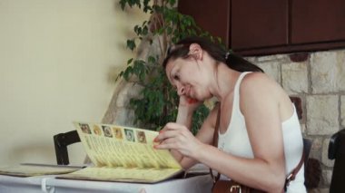 Oturma ve Yunan kafede menüyü okuyan güzel kadın.