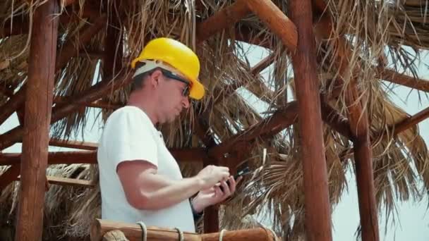Mann Architekt oder Ingenieur im Helm tippt SMS per Telefon. — Stockvideo