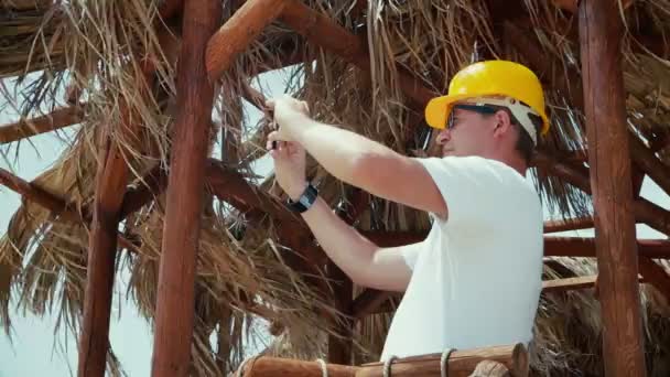 Hombre arquitecto o ingeniero en un casco estudia planos al aire libre, viendo planos, escribiendo, usando un teléfono inteligente, haciendo fotos por teléfono . — Vídeos de Stock