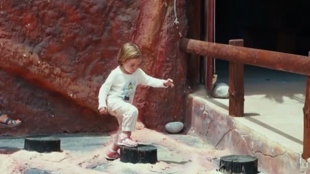 Little kid plays outdoor, jumping in the park. — Stock Video