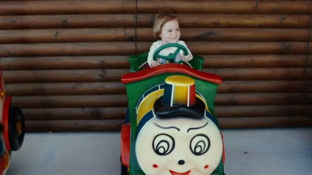 Criança montando em um carrossel. Girando, girando no parque infantil . Vídeo De Bancos De Imagens