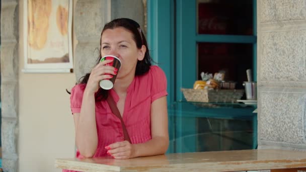 Assise dans un café, une belle jeune femme buvant du café ou du thé . — Video