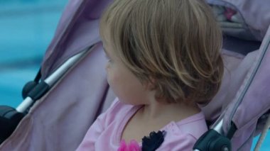 Bebek arabası havuzun yanında koltuklarda şirin bebek.