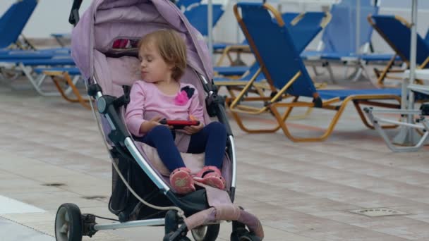 Söt baby platser i barnvagn vid poolen. — Stockvideo