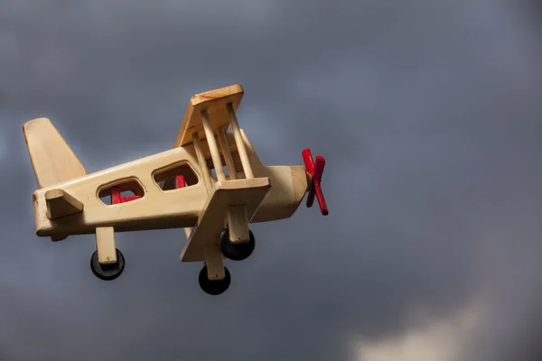 Holzflugzeug fliegt unter stürmischem Himmel - Seitenansicht — Stockfoto
