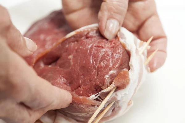 Colocando palitos de dentes para garantir o bacon em torno dos medalhões de lombo de vaca — Fotografia de Stock